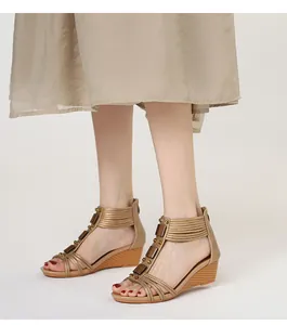 Detalle de sandalias de cuña doradas para mujer estilo romano con cremallera trasera