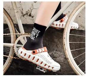 Detailansicht der weißen Herren-Gartenschuhe mit orangen Akzenten auf einem Pedal