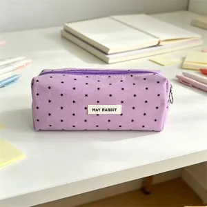 Detail view of purple canvas pencil case with star pattern and May Rabbit label on desk