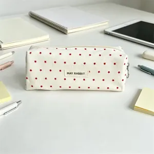 Close-up of cream canvas pencil case featuring red star patterns and a central May Rabbit label