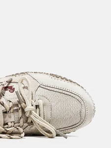 Macro view showing the beige leather and mesh material textures of an outdoor sneaker