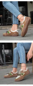 Close-up detail view of brown leather outdoor sneakers worn with blue denim jeans