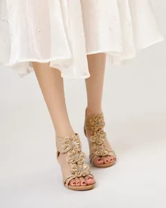 Close-up of bohemian wedge sandals with decorative flowers and pearl skirt detail.