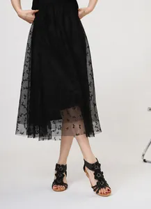 Detail of black Bohemian wedge sandals with floral accents styled with a mesh skirt.