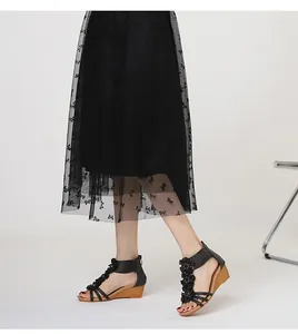 Side detail view of black Bohemian wedge sandals with floral accents paired with mesh skirt