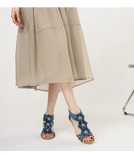 Detail shot of women's Bohemian blue floral wedge sandals paired with a beige skirt.