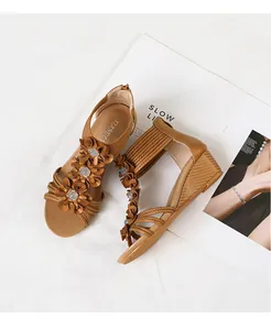 Detailed view of brown bohemian wedge sandals with decorative flowers and crystal accents