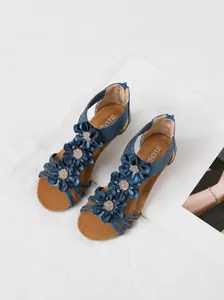 Overhead view of blue bohemian wedge sandals with three-dimensional flower decorations.