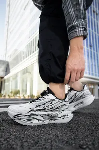 Close-up detail of men's breathable mesh running shoes featuring black brushstroke patterns