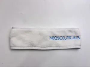 Close-up of a soft white microfiber spa headband with blue NEOSCEUTICALS embroidery