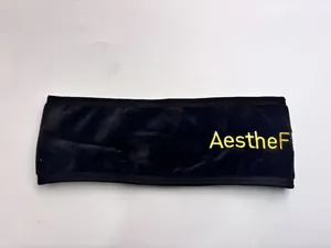 Macro view of black velvet yoga headband featuring yellow AestheF embroidered logo