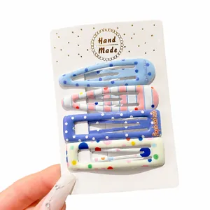 Set of four cute colorful polka dot and striped hair clips for girls on a display card