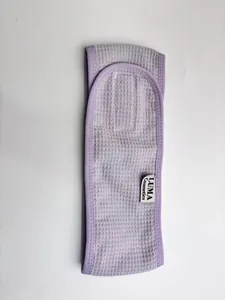 Macro view of purple waffle texture and brand tag on a cosmetic spa headband.
