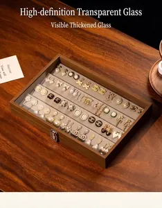 Detalle de gran organizador de joyas de madera con pendientes elegantes bajo tapa de vidrio.