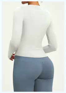 Rear detail of a slim-fit light grey long-sleeved yoga top paired with blue leggings.