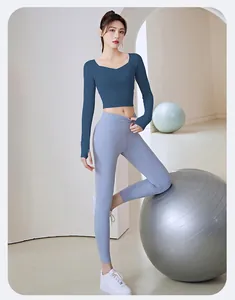 Fit woman wearing long-sleeve blue gym top and light blue leggings in minimalist studio