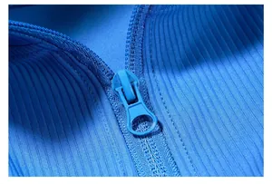 Close-up macro view showing blue ribbed knit fabric texture and zipper detail of athletic jacket
