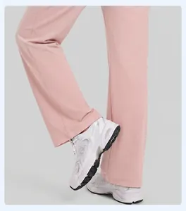 Detail view of pink loose-fit wide-leg yoga pants paired with white athletic sneakers.