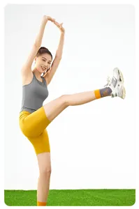 Femme en débardeur de sport gris élastique avec coussinets de poitrine intégrés s'étirant.