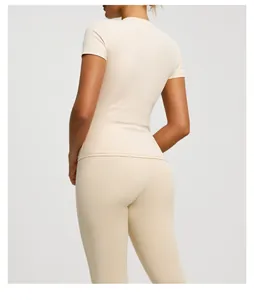 Back view of a sleek beige short-sleeve yoga top and matching leggings set on a fitness model.