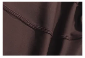 Close-up of premium brown yoga jacket fabric showing durable flatlock stitching details.