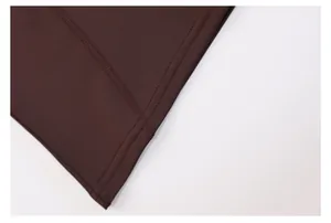 Detailed macro view showing the high-quality double-stitched hem of a brown yoga workout top