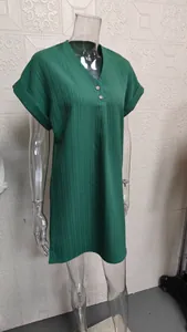 Primo piano di un abito verde con scollo a V e bottoni che mostra il tessuto operato.