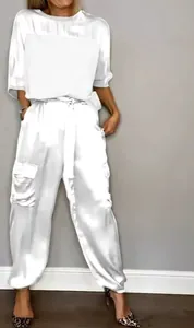 Full view of a model wearing a white satin two-piece set against a gray studio wall