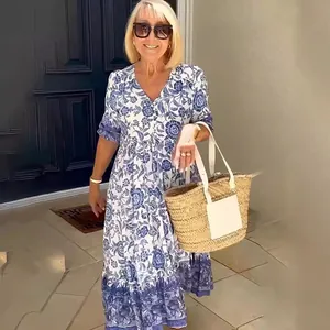 Elegant V-neck blue and white floral maxi dress for women worn on a sunny outdoor porch