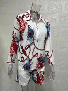 Detail of women's white two-piece set showing vibrant peacock feather print and zipper front