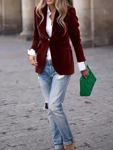 Stylish woman wearing a burgundy velvet blazer with ripped jeans in a street setting