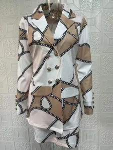 Détail d'une robe blazer croisée élégante avec boutons dorés et motif imprimé de chaînes noires.