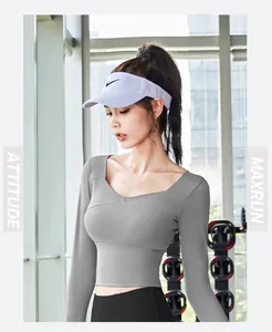 Detail view of grey long-sleeve cropped yoga top with crossover neckline in gym setting