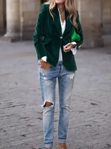 Detailed view of a dark green velvet blazer styled with light blue ripped jeans