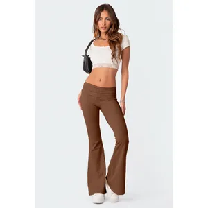 Modella con pantaloni a zampa marroni a vita bassa e set crop top bianco in pizzo