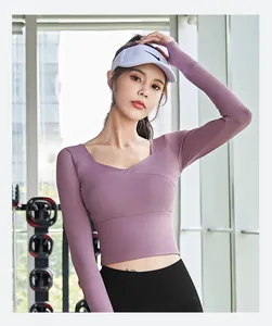 Detail view of a purple long-sleeve cropped yoga top featuring a cross-chest design