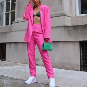 Gedetailleerde weergave van een modieus roze damespak met colbert en broek voor werk.