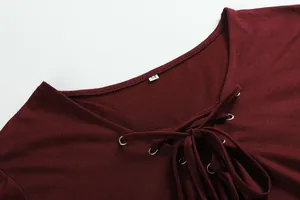 Close-up of burgundy V-neck top featuring silver metal eyelets and lace-up detail.