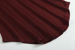 Macro detail view of the curved hemline and double-needle stitching on a burgundy top.