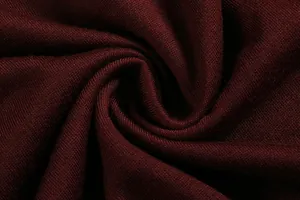 Close-up macro shot of soft burgundy knitted fabric texture with elegant swirl folds