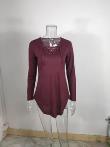 Detail view of burgundy long sleeve top with lace-up V-neck and curved hemline design.