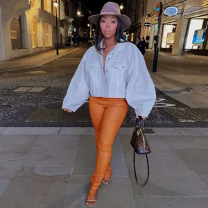 Detailed view of orange stretch PU leather pants with split hem and slim fit design.