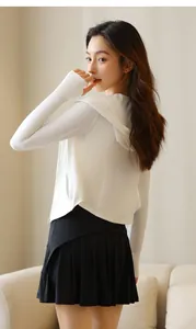 Back view of a woman wearing a white sun protection jacket and black pleated sports skirt set.