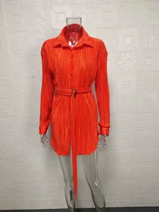 Close-up of vibrant orange pleated fabric on long sleeve shirt dress with adjustable belt