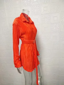 Detailed side view of a vibrant orange pleated long-sleeve shirt dress with matching belt