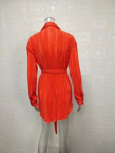 Detailed back view of vibrant orange pleated long sleeve shirt dress with a waist belt