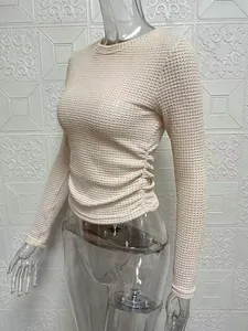 Detailed view of the elegant ruched side and textured knit fabric on a slim-fit cream top