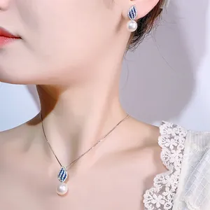 Dettaglio di un set di gioielli con perle eleganti e pendenti a foglia con pietre blu
