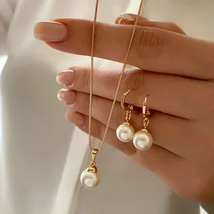 Primo piano di un elegante set di collana e orecchini di perle dorate tenuto in mano