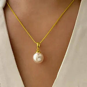 Primo piano di un'elegante collana a catena d'oro con ciondolo di perla bianca